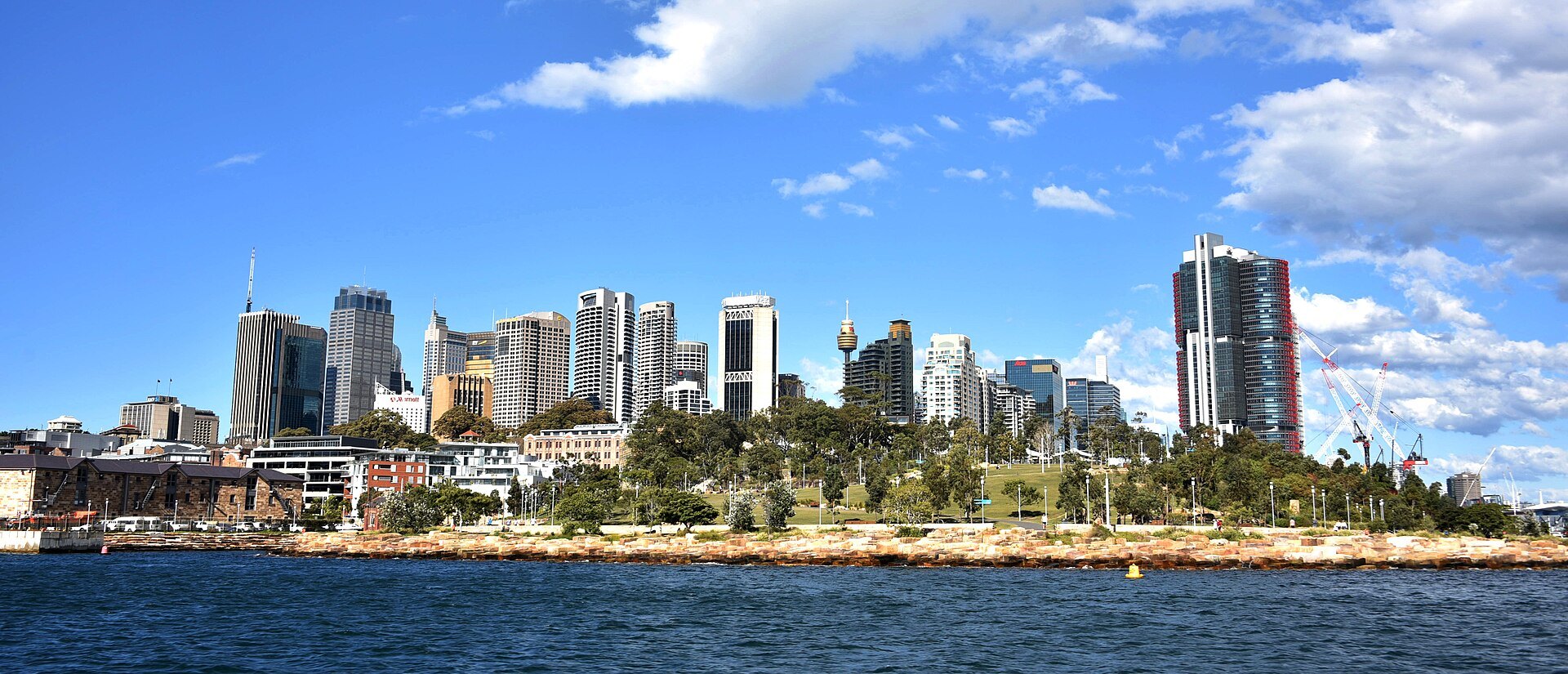 The city skyline seen across the water from the sandstone shoreline of Barangaroo Reserve