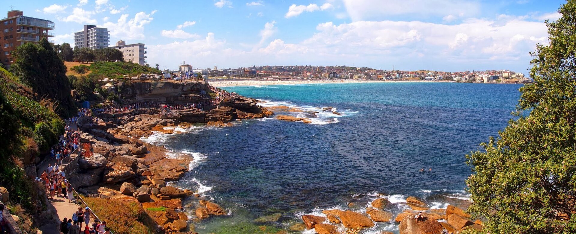 The coastal walk above red sandstone rocks, with a beach and headland further along
