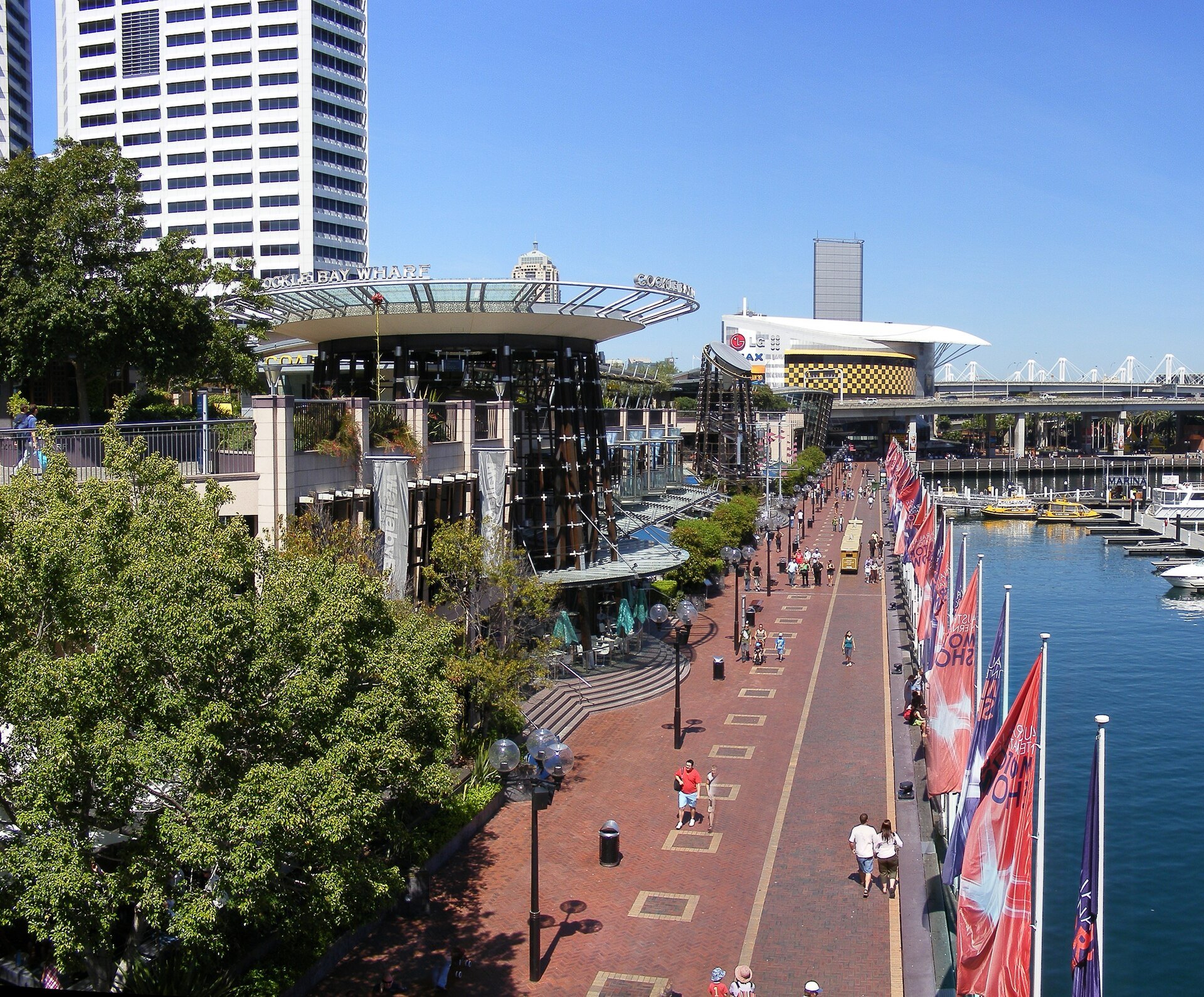 The promenade at Darling Harbour with flags along it and the water on one side