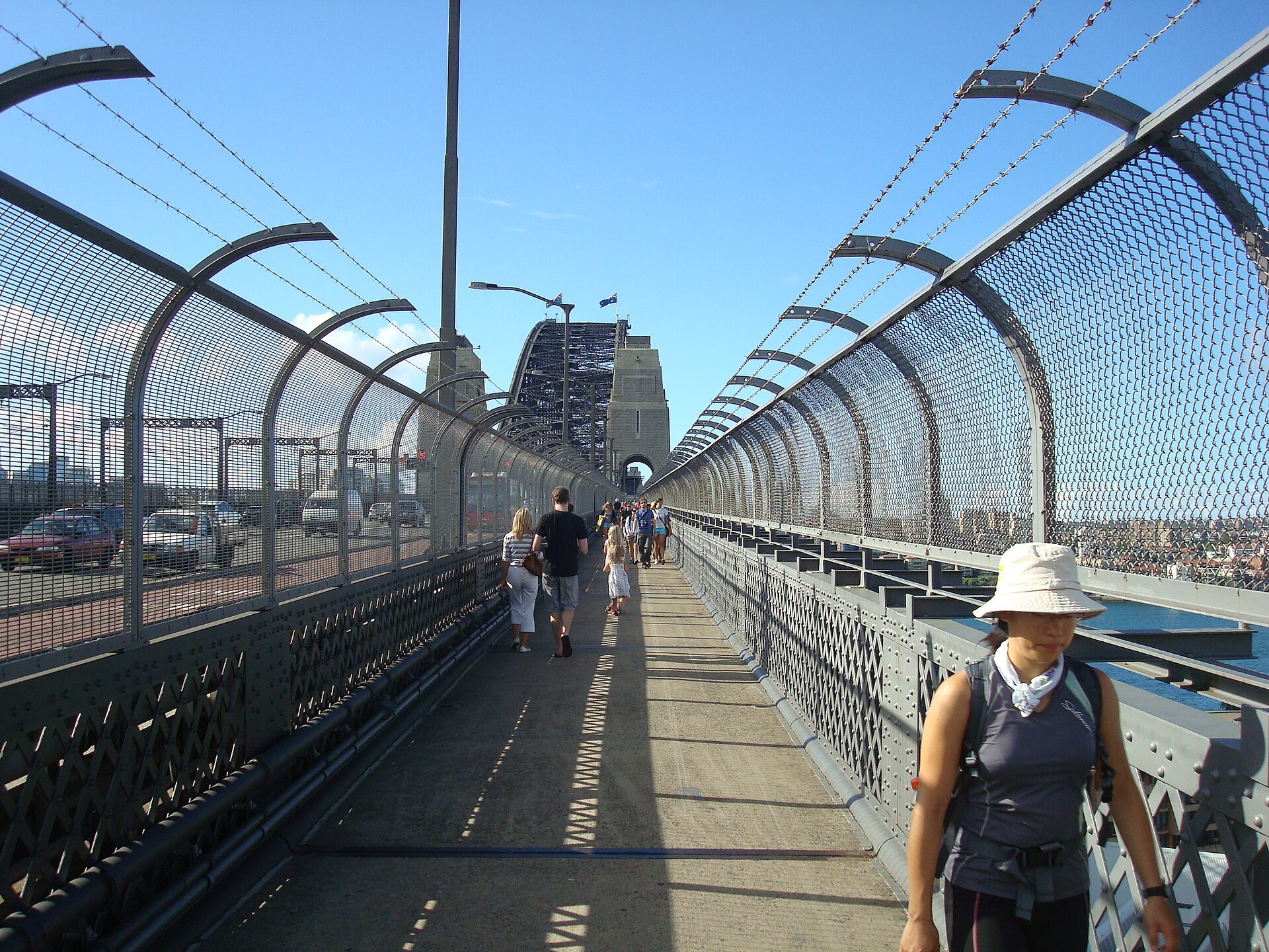 People walking the pedestrian path across the Harbour Bridge between the steel and the fence
