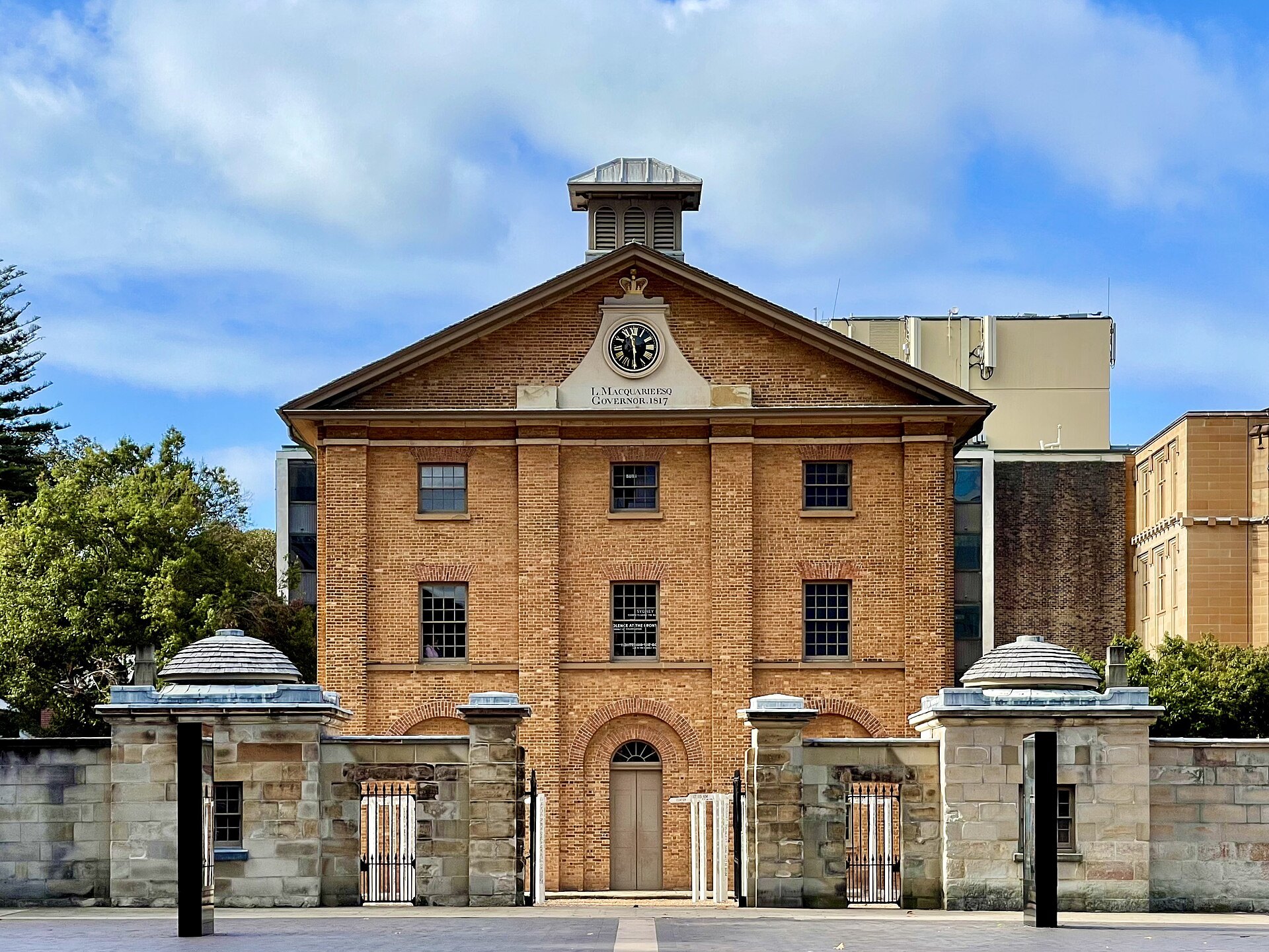 The brick front of Hyde Park Barracks behind its sandstone wall and gate piers