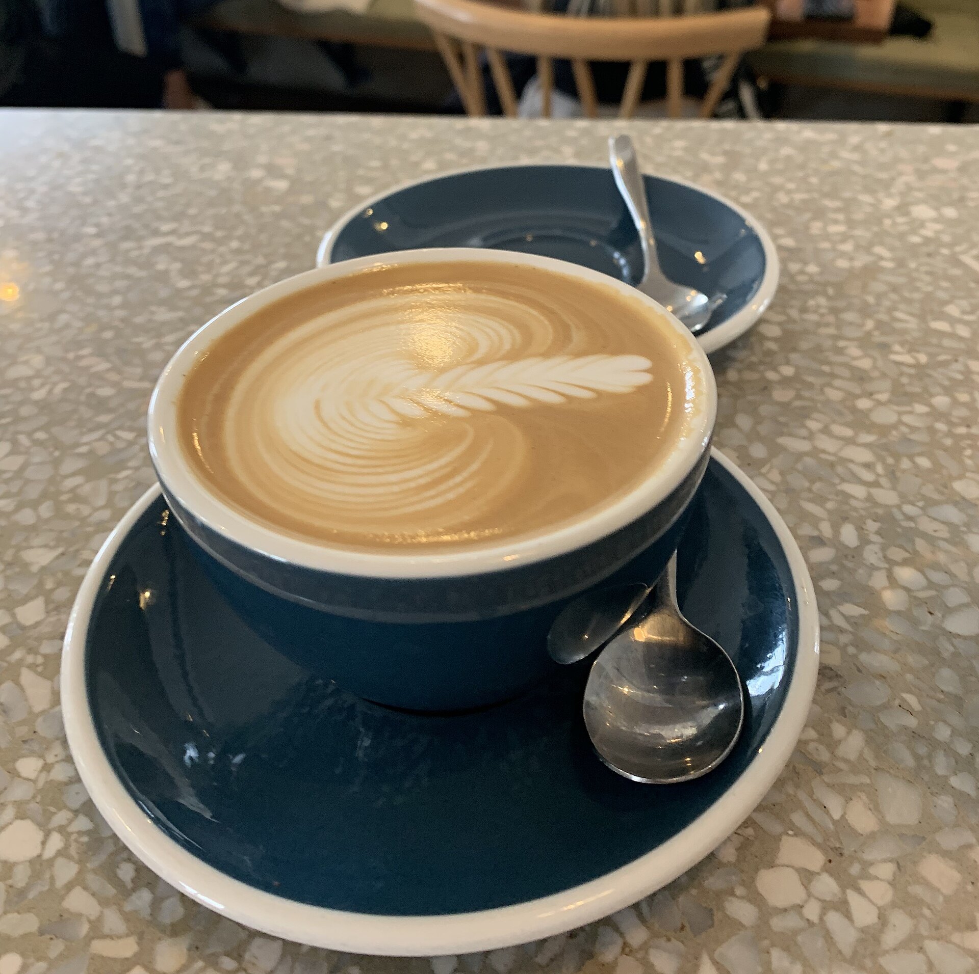 A flat white in a blue cup on a terrazzo café table