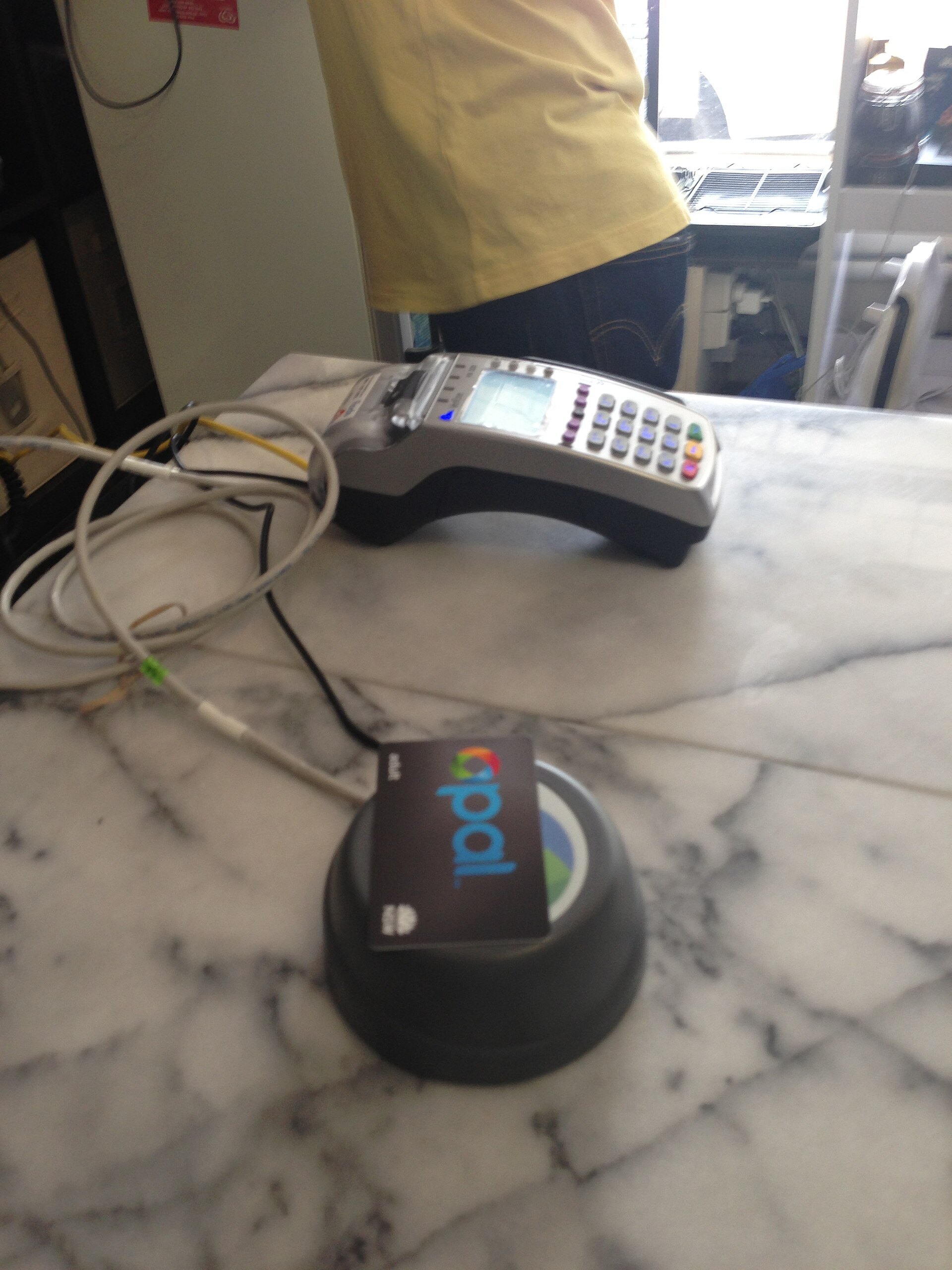 A card payment terminal and an Opal reader on a café counter