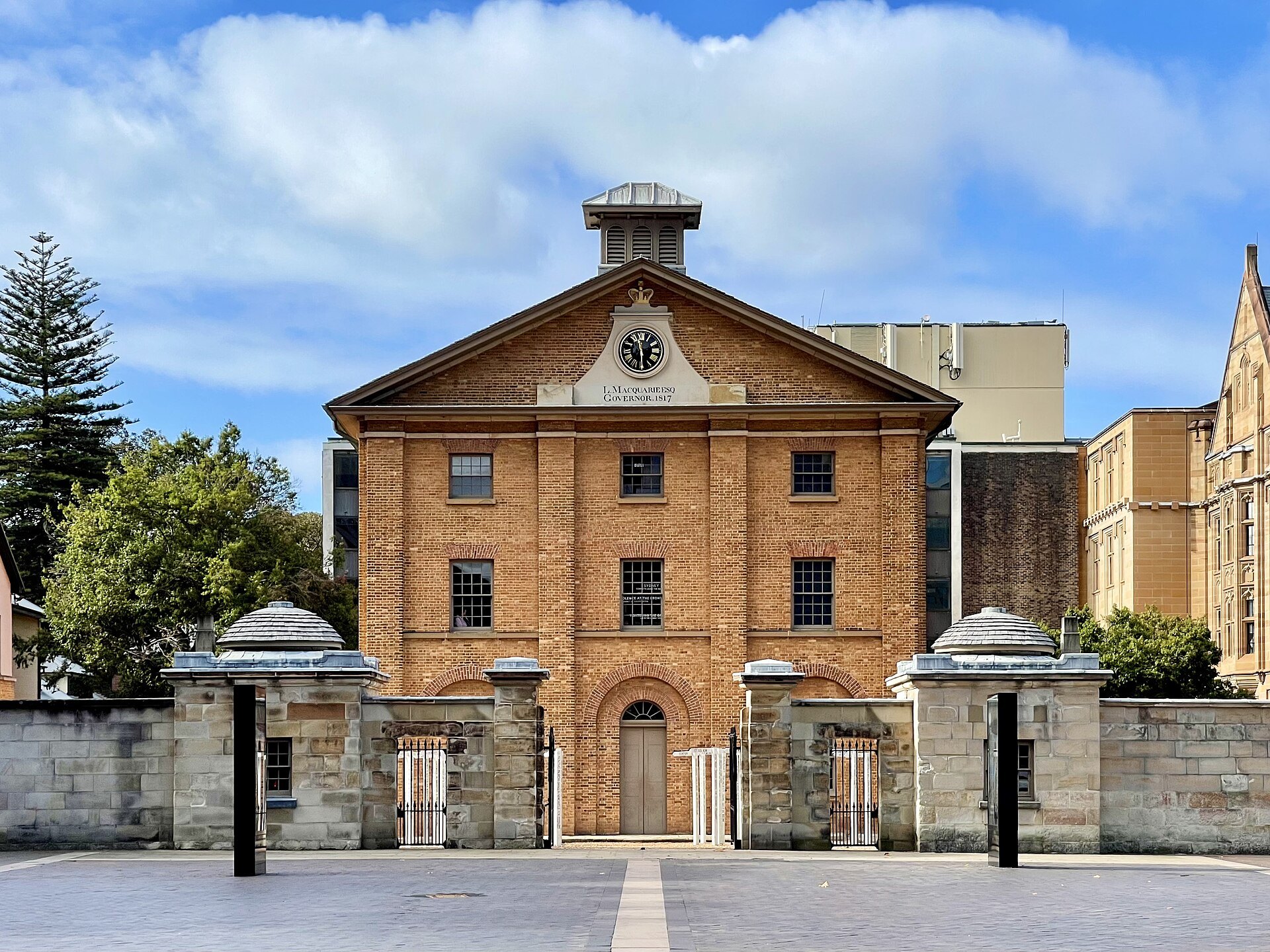 The brick front of Hyde Park Barracks behind its sandstone gates