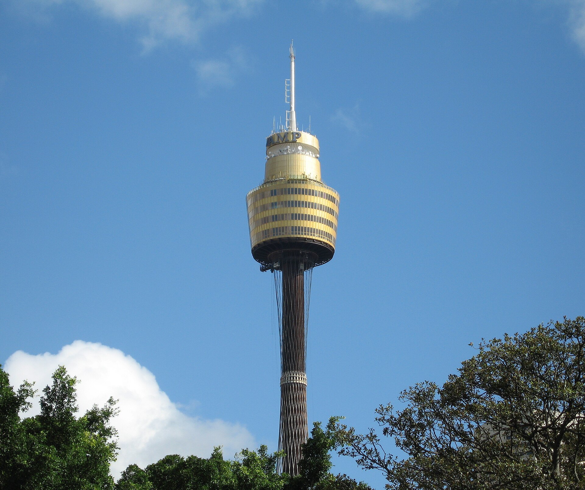 Sydney Tower's golden turret on its shaft, seen from below through trees